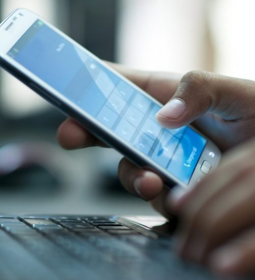 Businessman hand using laptop and mobile phone in office