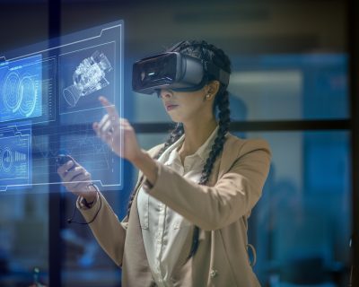 Female engineer wearing a virtual reality headset at work to explore an upcoming mechanical engineering project. She uses her hands to manipulate and explore the finer details.